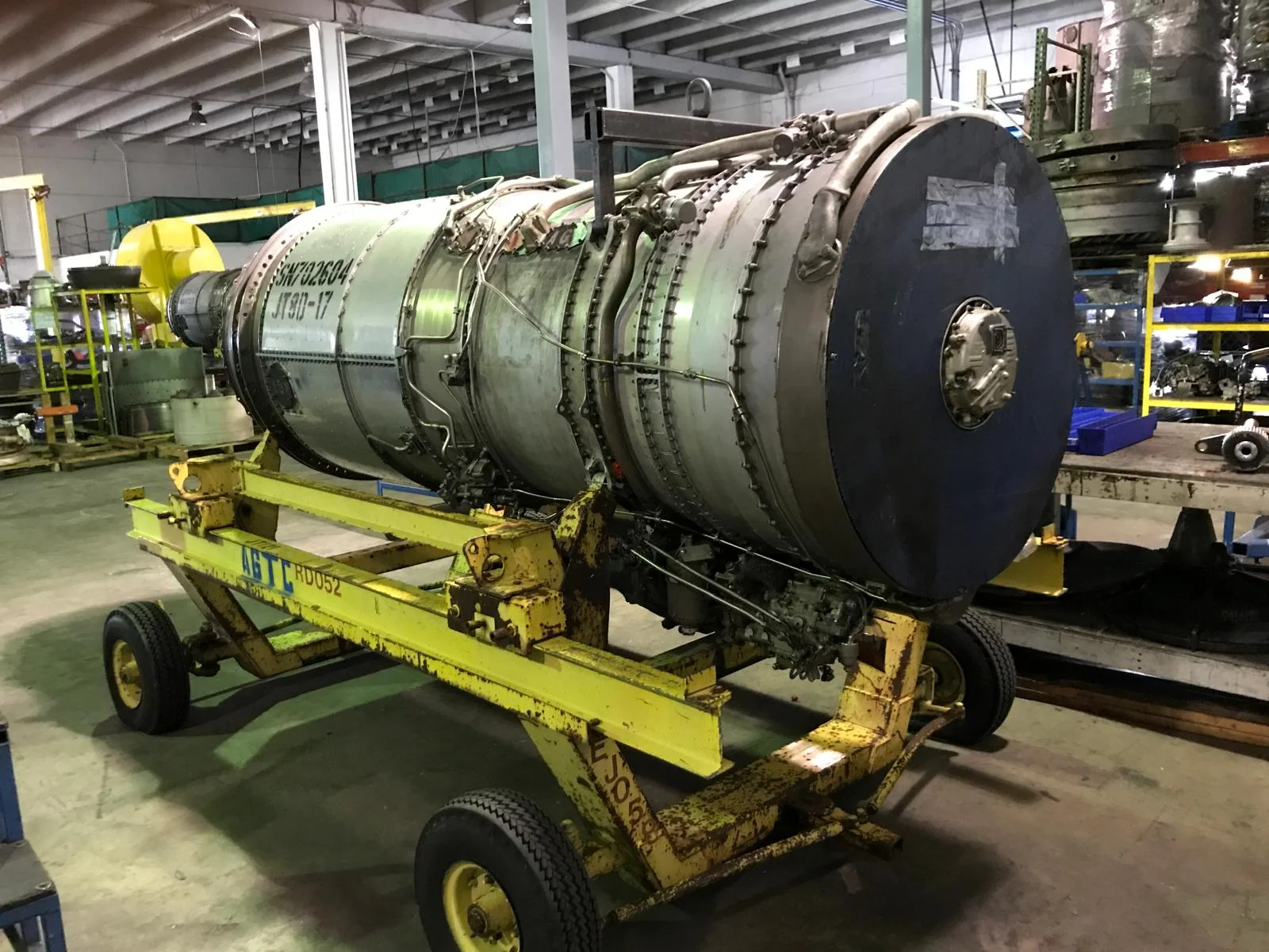Aircraft engine resting on a wheeled transport stand inside a workshop.