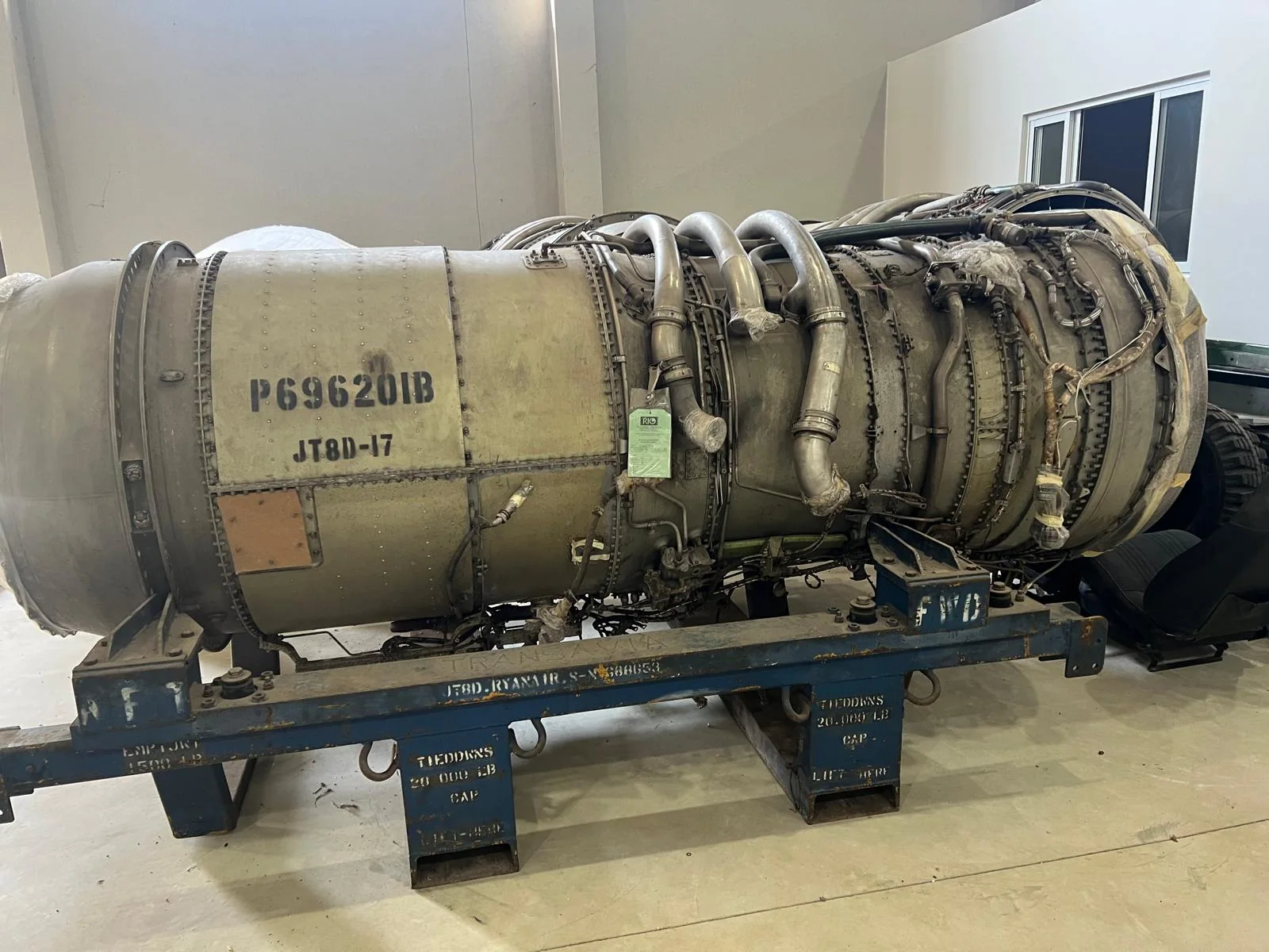 Aircraft engine on a metal transport frame in an indoor handling area.