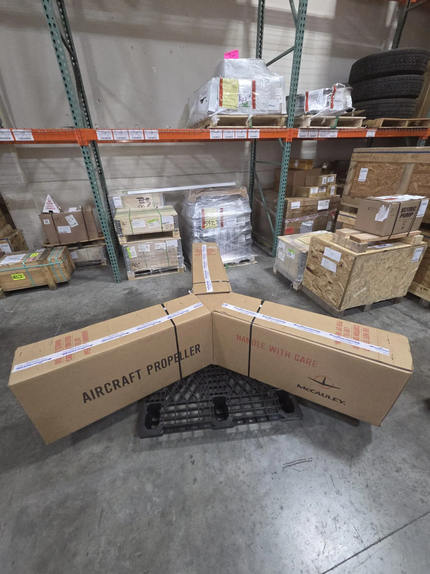 Long packages marked aircraft propeller arranged on a warehouse pallet.