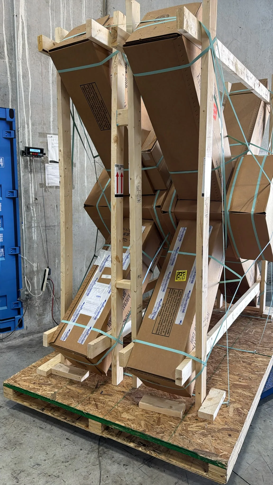 Long aerospace component packages secured in a tall wooden shipping frame.