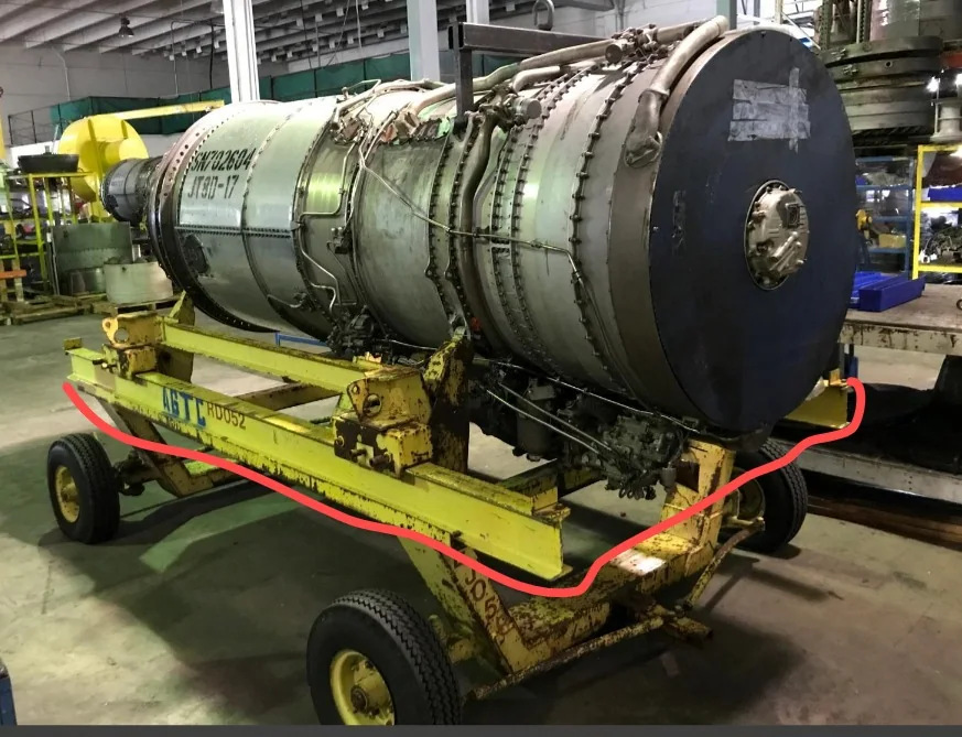 Aircraft engine on its wheeled support frame in a workshop.