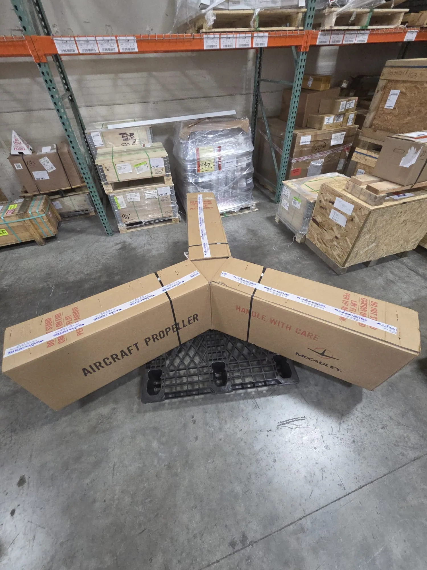Long aircraft propeller packages laid out in a warehouse.