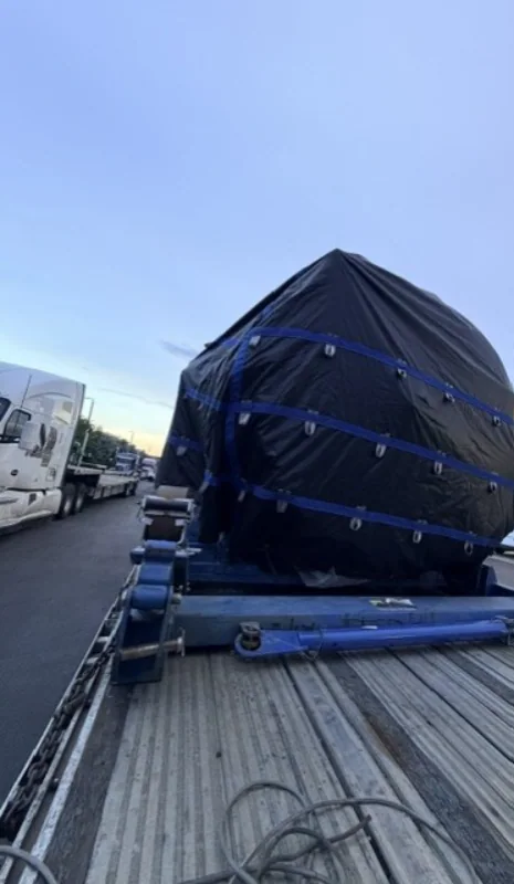 End view of a covered aerospace component on a trailer.