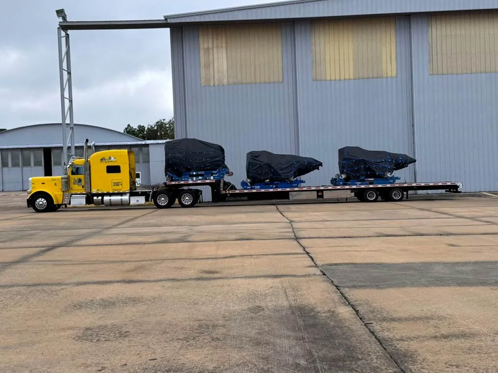 Multiple covered components secured on a long road trailer.