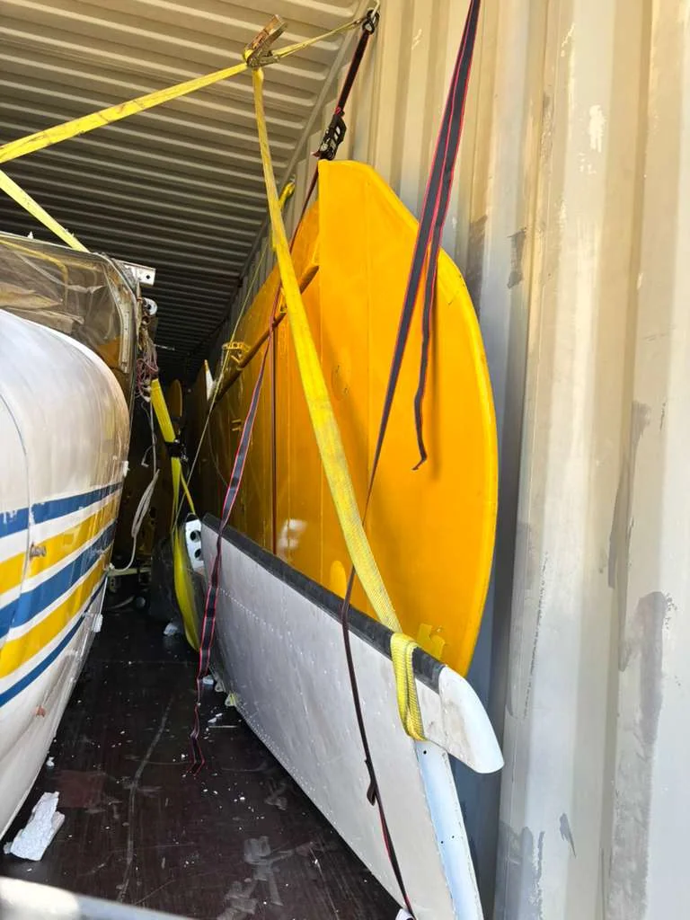 Side view of a small aircraft and its wings inside a container.