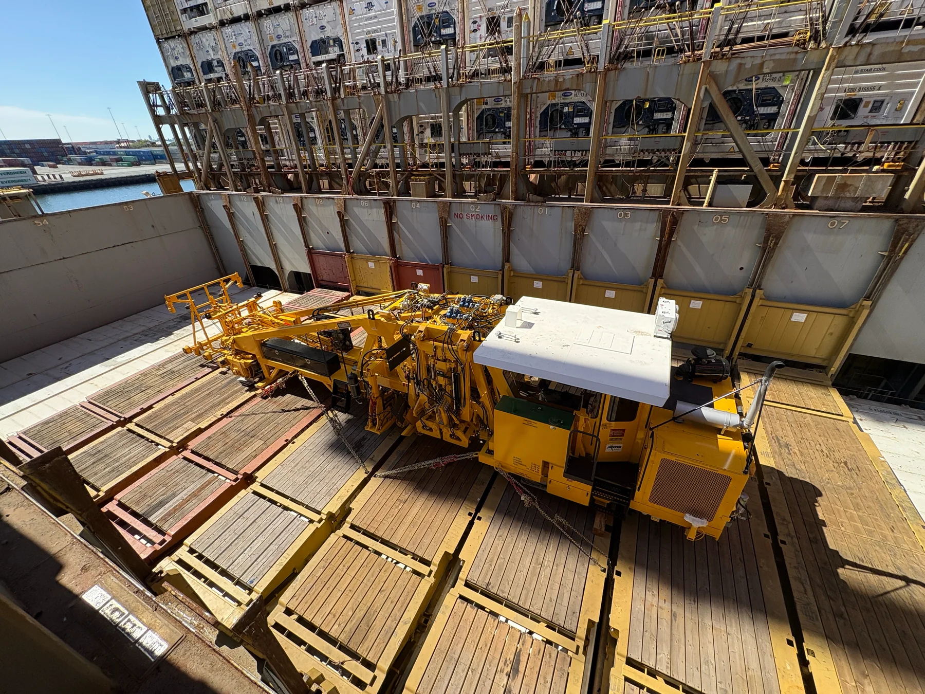 Yellow railway equipment secured on a cargo vessel deck.