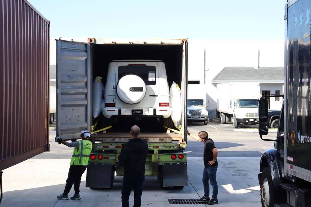 Team supervising the loading of a vehicle into a container in the United States